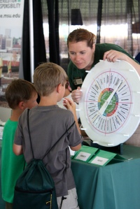 Michigan State University Extension educator Sara Keinath explains the 4-H life-skills wheel to two young attendees of Ag Expo. 